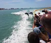 A group of people enjoys a sunny day on a speeding yellow boat named Sea Screamer on the water with an American flag flying at the stern