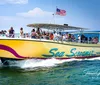 A group of people enjoys a sunny day on a speeding yellow boat named Sea Screamer on the water with an American flag flying at the stern