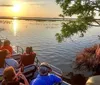 A group of tourists enjoy a ride on an airboat likely in a swamp or marshland with one person excitedly raising their hand