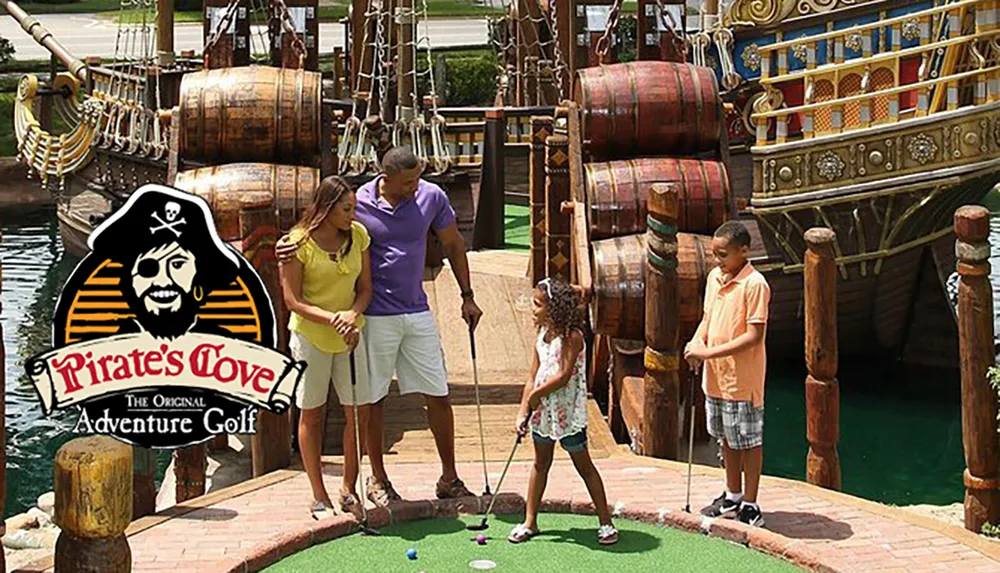 A family is enjoying a game of miniature golf at a pirate-themed adventure golf course with a large pirate ship in the background
