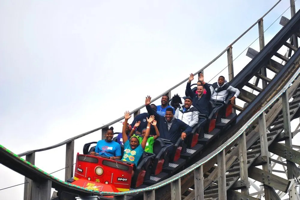 People on a roller coaster are excitedly raising their hands as they descend a slope