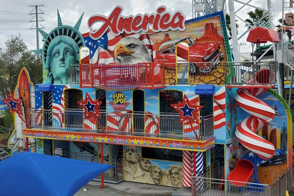 The image shows a colorful amusement park attraction featuring patriotic American symbols like the Statue of Liberty an eagle and the US flag