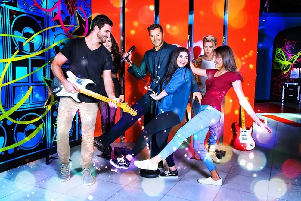 A group of people is enjoying a vibrant karaoke or music-themed party with one playing an electric guitar and others singing and dancing against a backdrop of colorful graffiti art