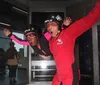 Two people are indoor skydiving in a vertical wind tunnel seemingly enjoying an exhilarating flying experience