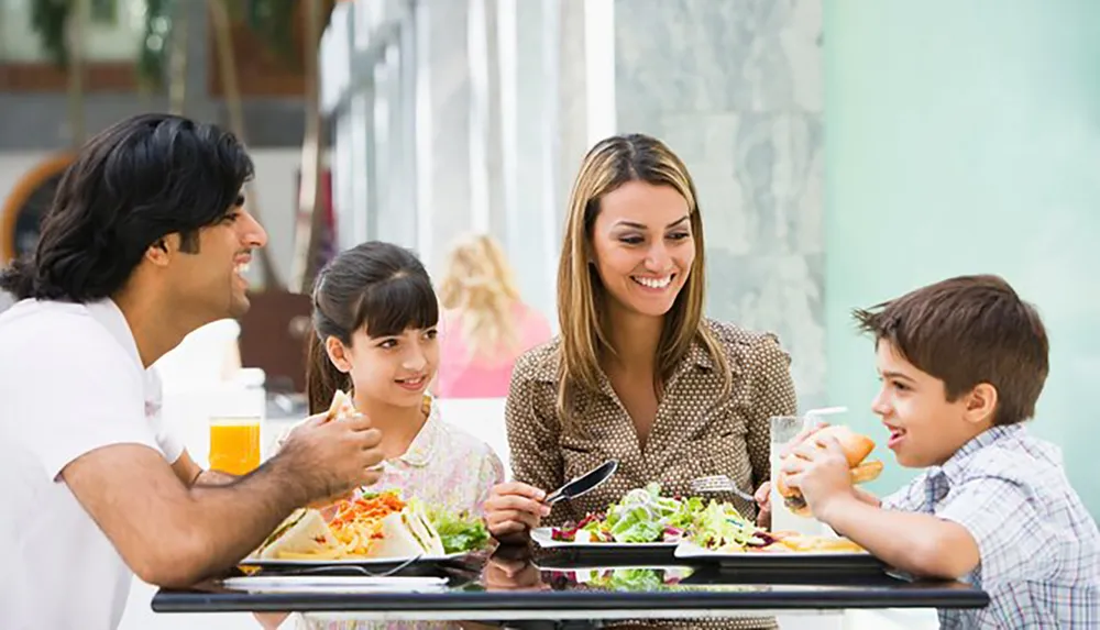 A family of four is enjoying a meal together at an outdoor dining area
