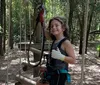 Three people are climbing a tall wooden structure outdoors secured with harnesses and ropes displaying expressions of enjoyment and adventure