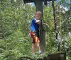 Three people are climbing a tall wooden structure outdoors secured with harnesses and ropes displaying expressions of enjoyment and adventure