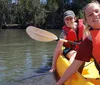 A person on a kayak is reaching out towards a manatee swimming close by in clear water