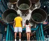 A group of people are enjoying their visit to a space center with rockets on display in the background