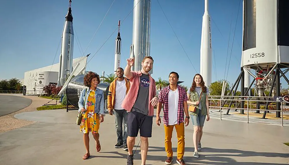 A group of people are enjoying their visit to a space center with rockets on display in the background