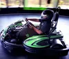 A person wearing a helmet is driving a go-kart on an indoor track conveying a sense of speed and motion