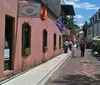 People stroll through a lively street lined with shops and restaurants on a sunny day