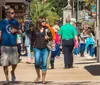 People stroll through a lively street lined with shops and restaurants on a sunny day