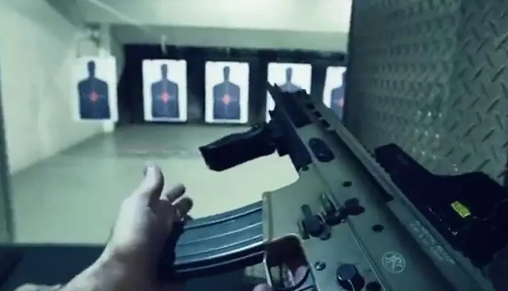 This image shows a persons hand inserting a magazine into a firearm at a shooting range with targets in the background