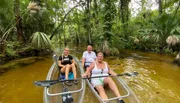 Three individuals are enjoying a canoe trip on a tranquil, tree-lined river.