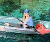 A group of smiling people are enjoying kayaking and paddleboarding on a sunny day in clear water with lush greenery in the background