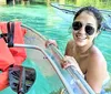 A group of smiling people are enjoying kayaking and paddleboarding on a sunny day in clear water with lush greenery in the background