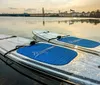 Three people are stand-up paddleboarding on a calm river with clear water and lush greenery in the background