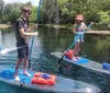 Three people are stand-up paddleboarding on a calm river with clear water and lush greenery in the background