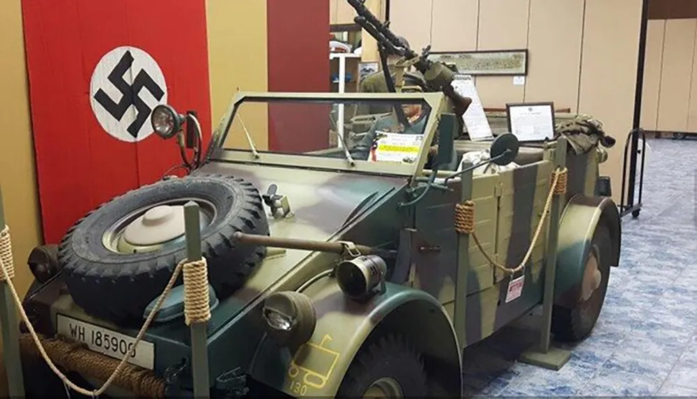 The image shows a military vehicle likely from World War II with historical markings and a flag with a swastika on display suggesting it is part of a historical exhibit or collection