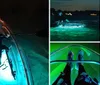 A person is kayaking at night in a clear kayak illuminated from within highlighting the water below