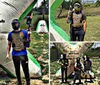 Two people wearing masks and protective vests are holding paintball guns standing next to an inflatable barrier in a paintball arena
