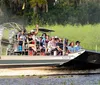 A group of tourists wearing headphones is enjoying a high-speed ride on an airboat through a marshy landscape