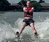 A person is captured mid-fall while waterskiing losing grip on the handle with water spraying around