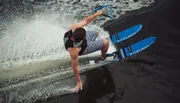 A person is captured mid-fall while waterskiing, losing grip on the handle with water spraying around.