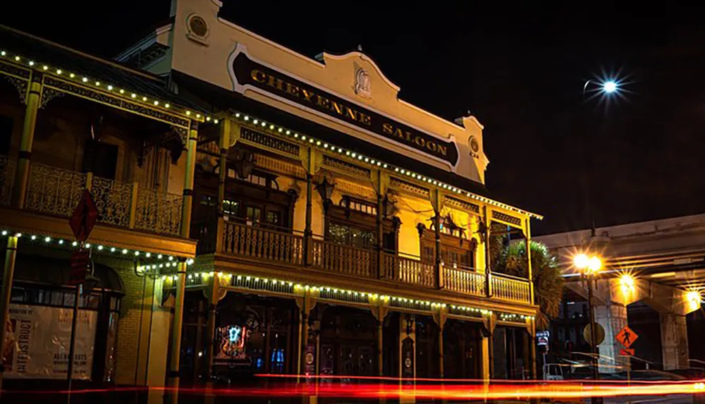 The image shows the illuminated faade of the Cheyenne Saloon at night with light trails from passing vehicles