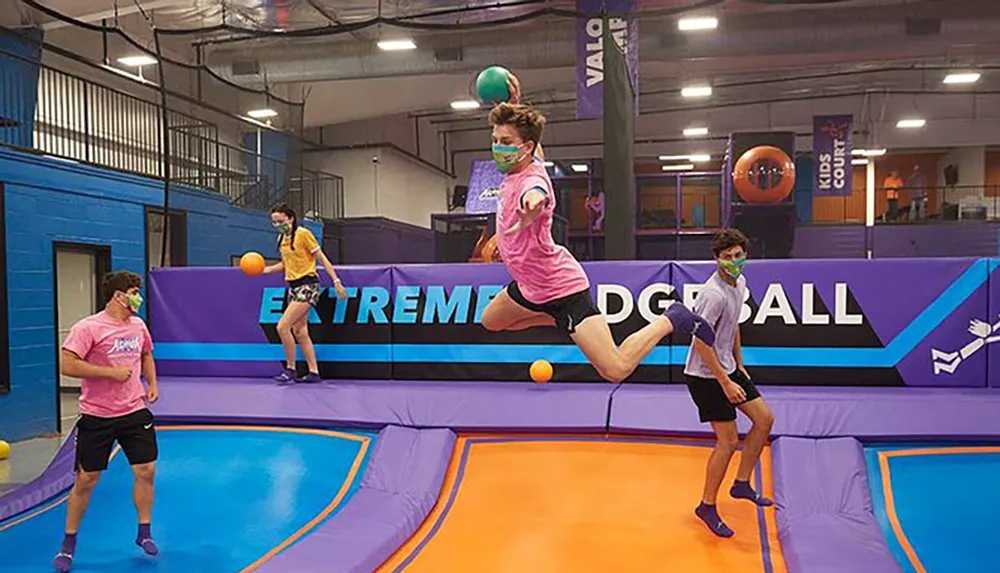 People are playing dodgeball on trampolines in an indoor trampoline park
