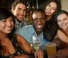 A group of five smiling friends enjoying drinks together at a social gathering