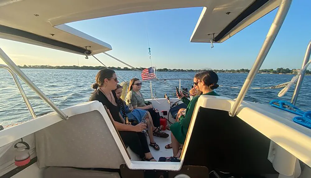 A group of people are enjoying a boat ride on a sunny day with an American flag fluttering in the background