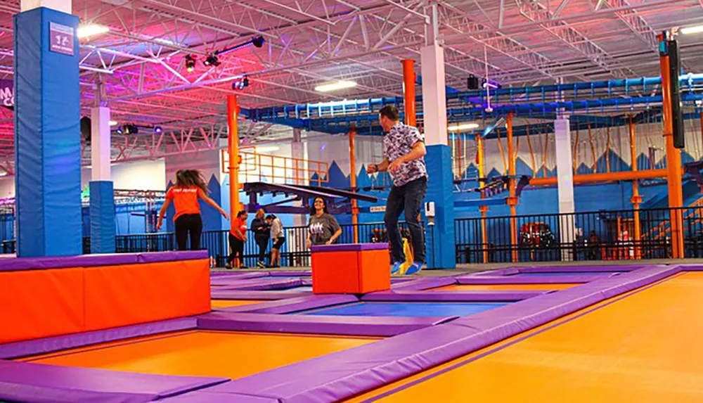People are enjoying various activities in a bright and colorful indoor trampoline park