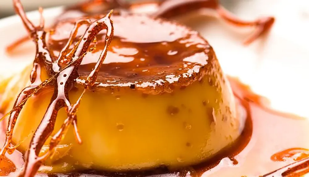 The image shows a caramel flan with a glossy top and decorative caramelized sugar garnish
