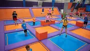 Children and adults are enjoying themselves while jumping on a colorful indoor trampoline park.