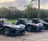 A person is driving a three-wheeled Polaris Slingshot on a bridge with a city skyline in the background