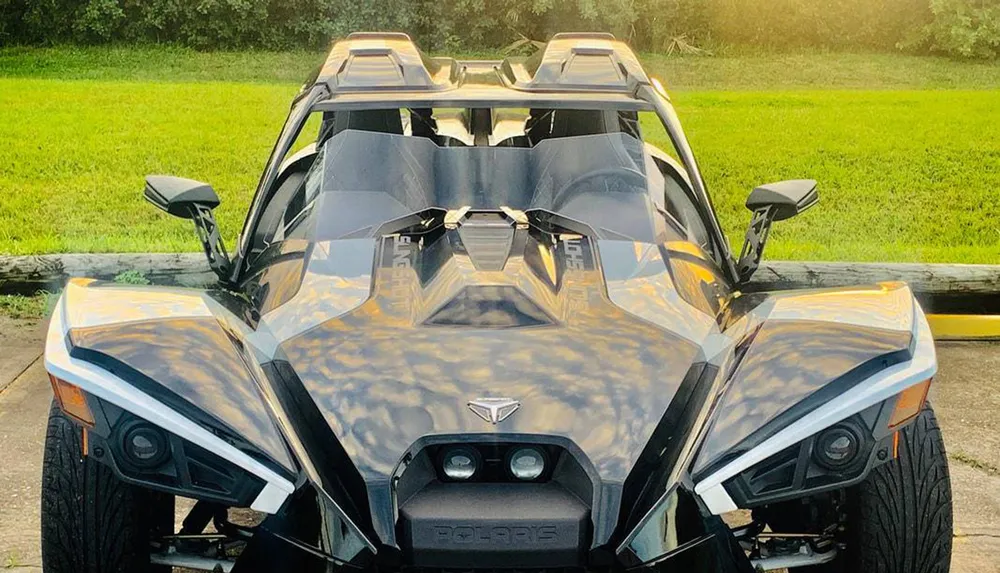 The image shows a front view of a modern angular Polaris Slingshot three-wheeled vehicle with a distinctive sporty design parked outdoors