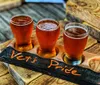 Three glasses of beer are presented on a wooden board labeled Vets Pride possibly indicating a themed beer tasting or a toast to veterans