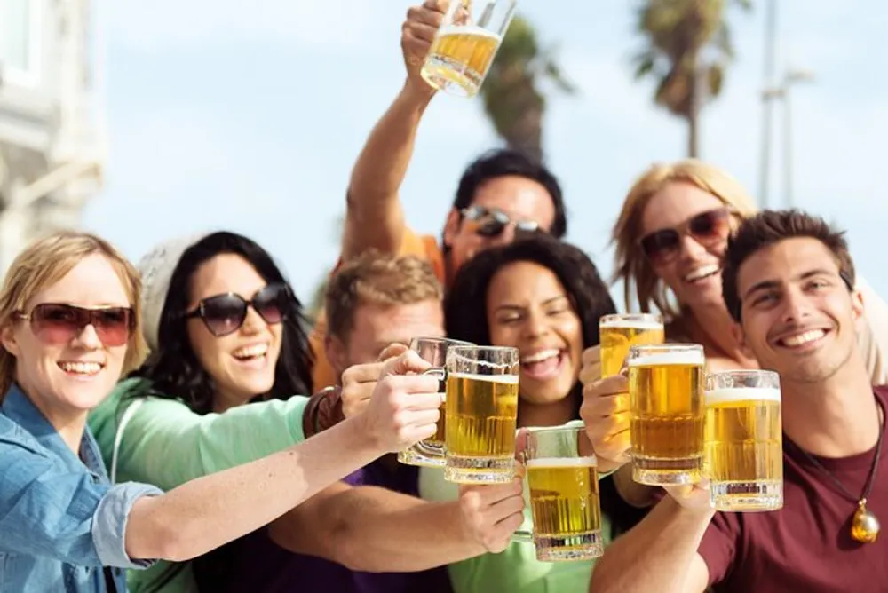 A group of cheerful people are toasting with glasses of beer outdoors