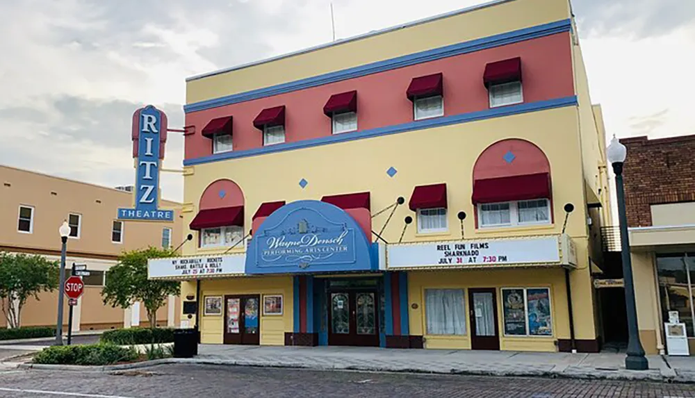 The image shows the front facade of the Ritz Theatre which is featuring films as advertised on its marquee sign with a stop sign and street lamp visible in the foreground