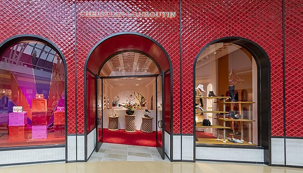 The image shows a stylish Christian Louboutin store with a characteristic red and black facade displaying luxury shoes and accessories