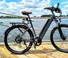 A person is seated on a yellow electric bicycle with a rear cargo rack holding the handlebars and appears ready to ride