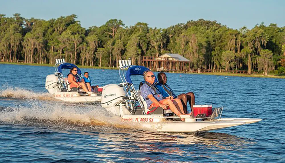 This image shows two motorboats cruising side by side on a calm lake each carrying passengers who seem to be enjoying a sunny day on the water