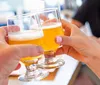 Two people are toasting with glasses of beer in a social setting