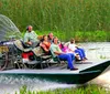 A group of people is enjoying a ride on a large airboat through a grassy wetland area