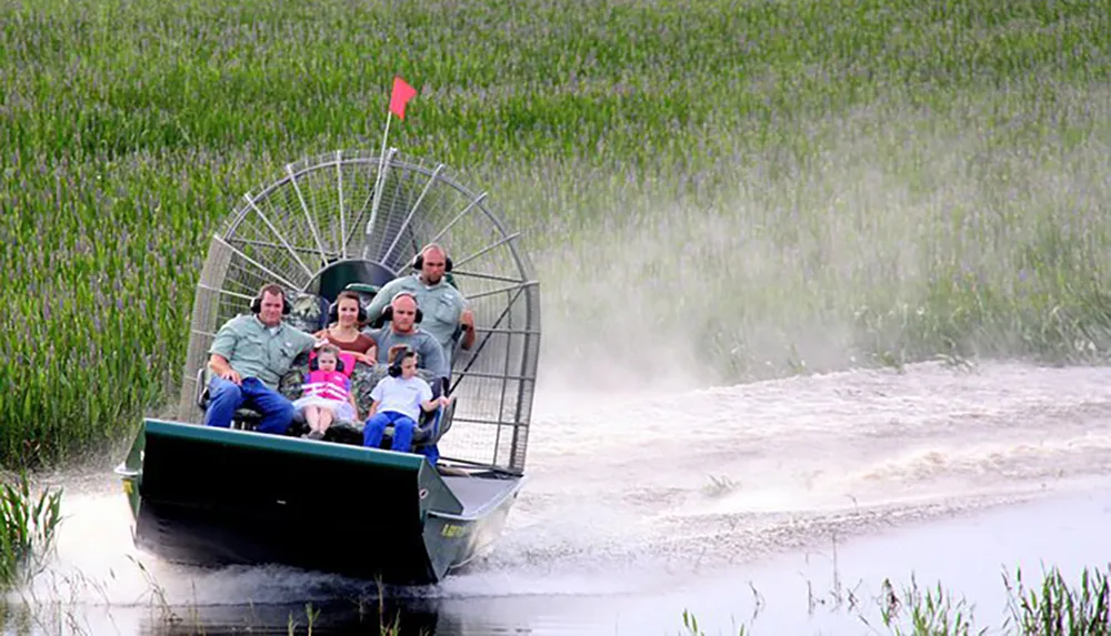 A group of people is riding through marshy wetlands in an airboat