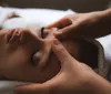A person is receiving a relaxing facial massage lying down with their eyes closed