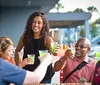 A group of people are enjoying drinks and smiling together at an outdoor table