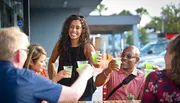 A group of people are enjoying drinks and smiling together at an outdoor table.